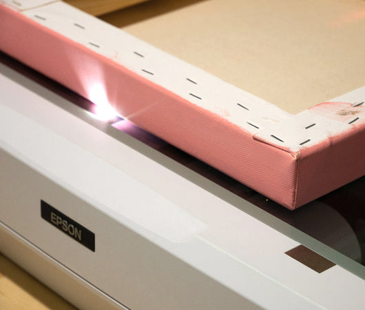 A painted canvas being scanned on an epson scanner