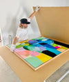 A man packing a bright and colourful canvas into a large cardboard box